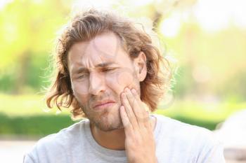 Young man suffering from toothache outdoors�