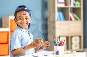 Cute African-American boy painting at home�