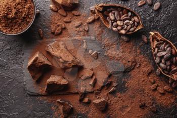 Composition with cocoa powder, beans and chocolate on table�