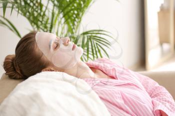 Young woman with sheet facial mask at home�
