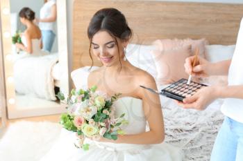 Professional makeup artist working with young bride at home�