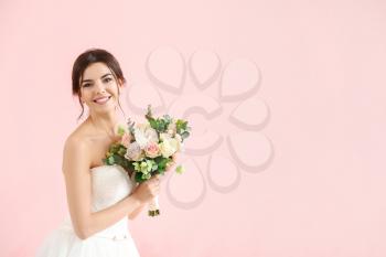 Beautiful young bride with bouquet of flowers on color background�