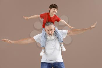 Funny little boy with grandfather on color background�