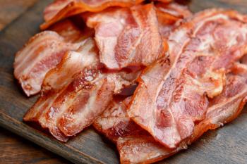 Fried bacon on wooden board, closeup�