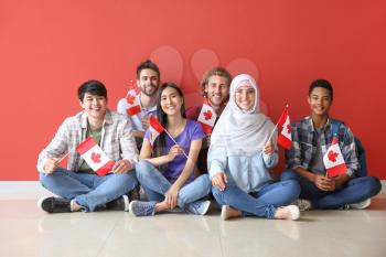 Group of students with Canadian flags sitting near color wall�