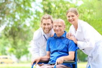 Elderly man with caregivers in park�