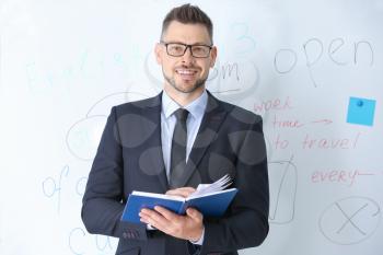 Handsome male teacher near blackboard in classroom 