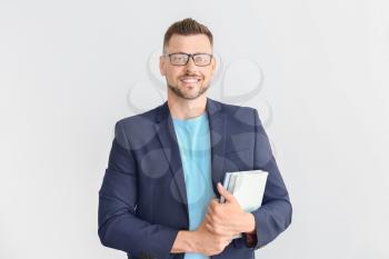 Handsome male teacher with books on light background�