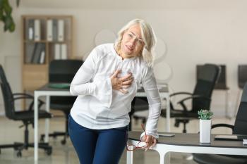 Mature woman suffering from heart attack in office�