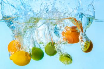 Falling of different fruits into water on light background�
