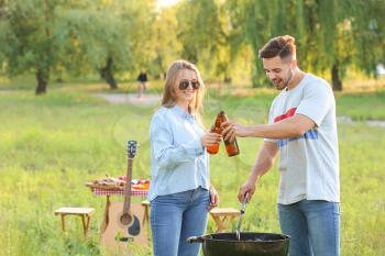 Young couple drinking beer at barbecue party outdoors�