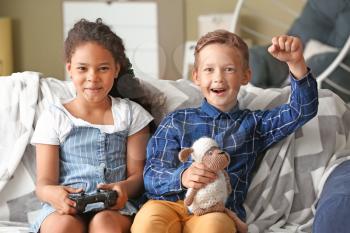 Happy adopted children playing video game in their new home�