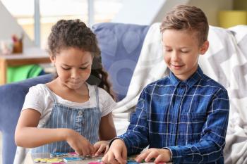Happy adopted children doing puzzle in their new home�