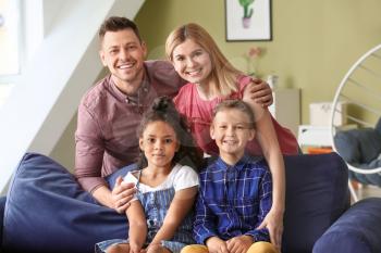 Happy couple with little adopted children at home�