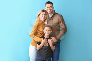 Happy couple with little adopted boy on color background�