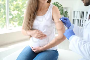 Doctor vaccinating pregnant woman in clinic�