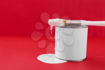 Can of paint and brush on color background�