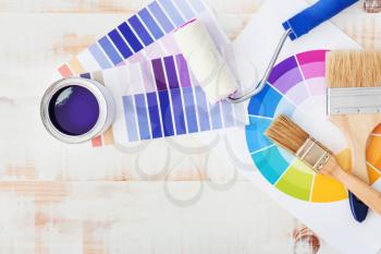 Can of paint with supplies and palette samples on light background�