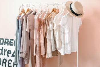 Rack with clothes near color wall in room�