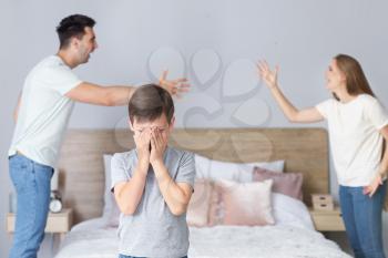 Sad little boy and his quarreling parents at home�
