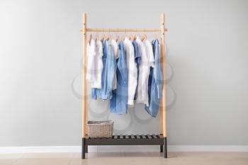 Rack with hanging clothes near light wall�