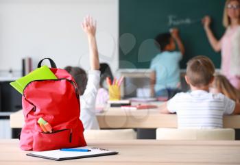 School backpack with stationery on table in classroom�