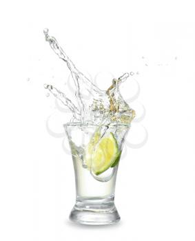 Dropping of lime into glass with tasty tequila on light background�