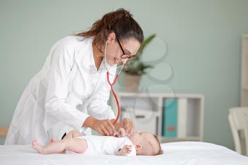 Pediatrician examining little baby in clinic�