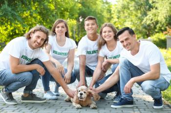 Volunteers with cute dog outdoors�