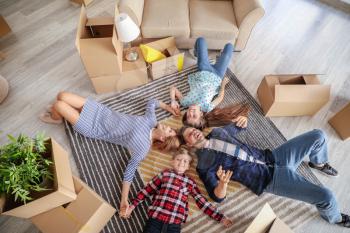 Happy family with belongings lying on floor in their new house�