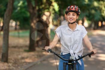 Young woman riding bicycle outdoors�