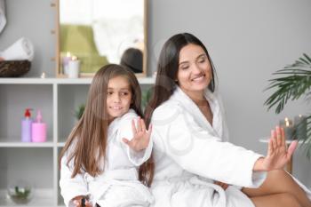 Mother and her little daughter in bathrobes doing nails at home�
