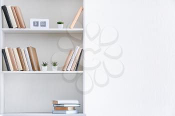 Shelf unit with books near white wall�