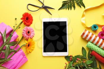 Modern tablet computer with supplies of florist on color background�