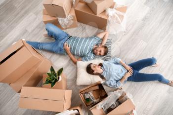Happy young couple with belongings lying on floor in their new house�