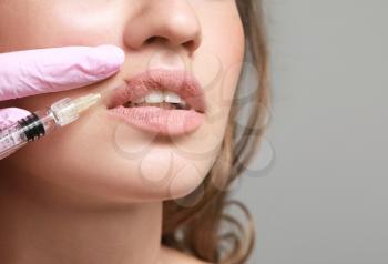 Young woman receiving injection of filler in lips, closeup�
