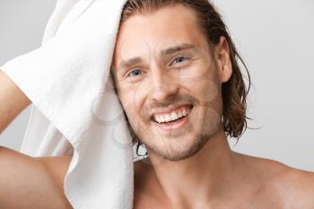 Handsome man wiping hair after washing against grey background�