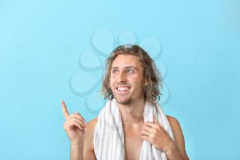 Handsome young man after washing hair pointing at something against color background�