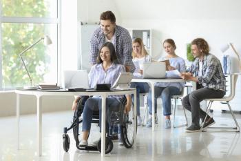 Handicapped young woman with colleague working in office�