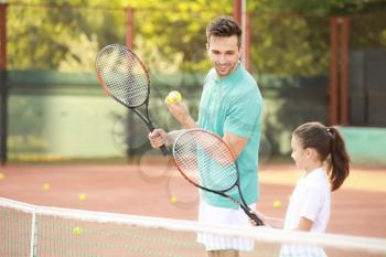 Little girl and her father playing tennis on court�