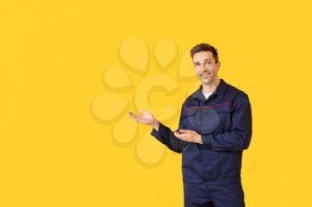 Male car mechanic showing something on color background�