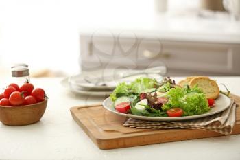 Plate with tasty salad on table in kitchen�