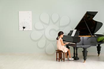 Little girl playing grand piano at home 