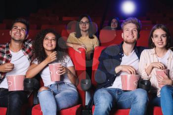 Friends with popcorn watching movie in cinema�
