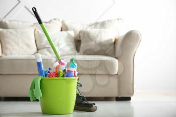 Bucket with cleaning supplies on floor in room�