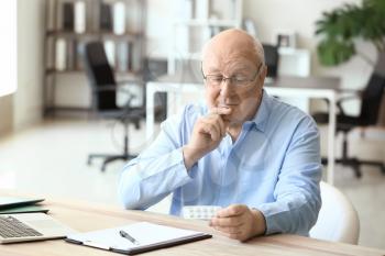 Elderly man taking medicine in office�