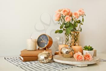 Beautiful burning candles with rose flowers, books and alarm clock on table�