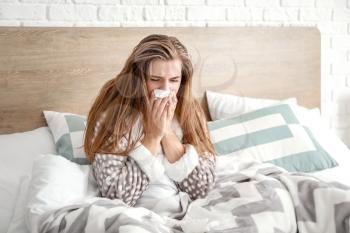 Sick woman sitting on bed at home�