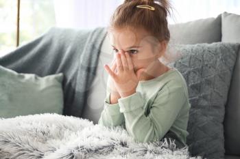 Sick little girl sitting on sofa at home�