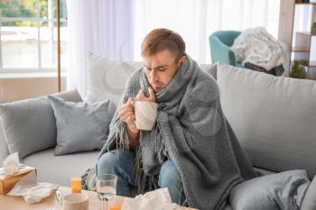 Sick man drinking hot tea at home�